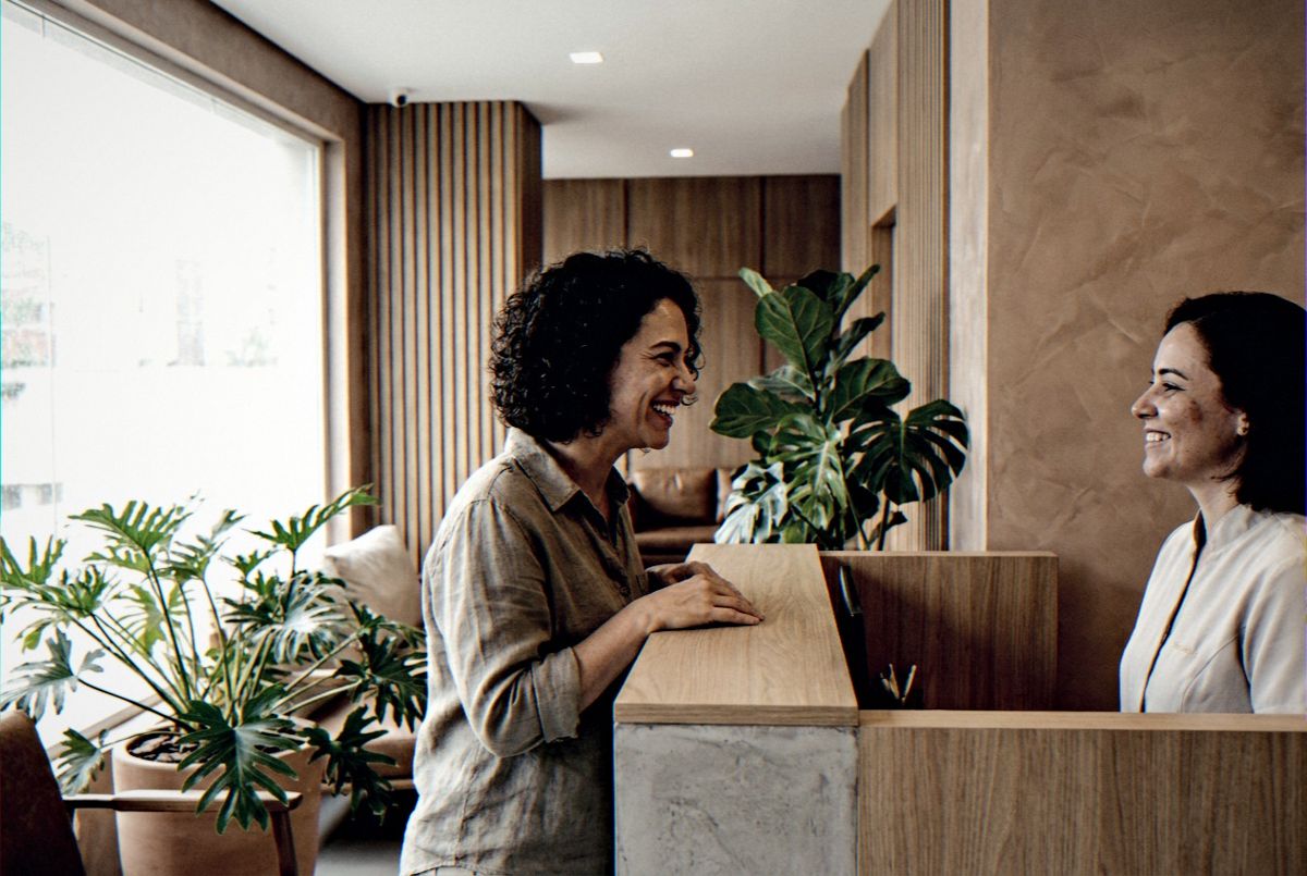 Paciente chegando à recepção de uma clínica, à vontade e sorrindo